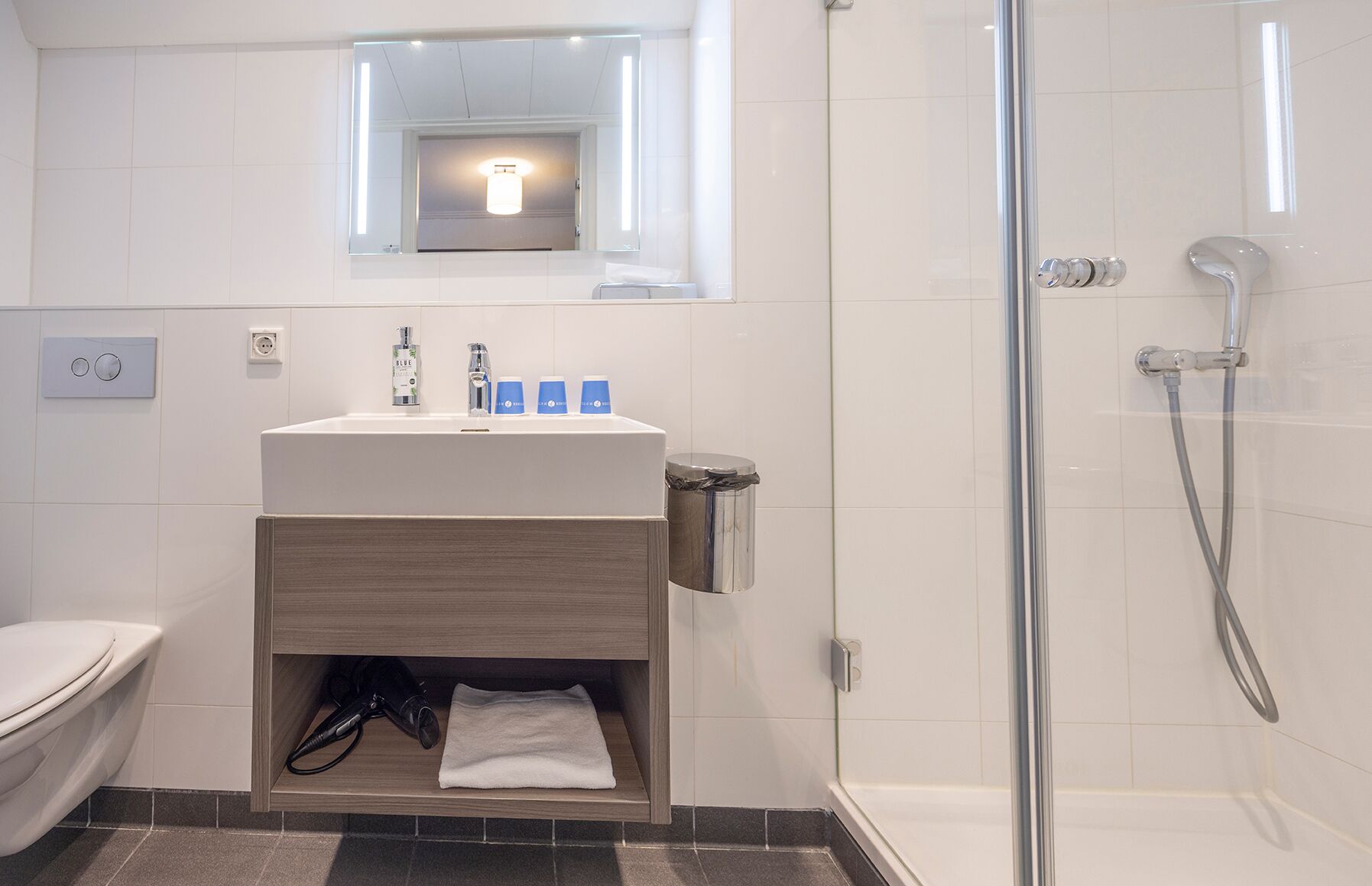 A modern bathroom with a white sink, mirror, and shower.