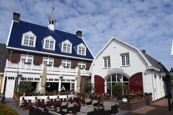 A building with a blue tiled roof and a white facade, featuring a sign that reads "Riva Wine Lounge."