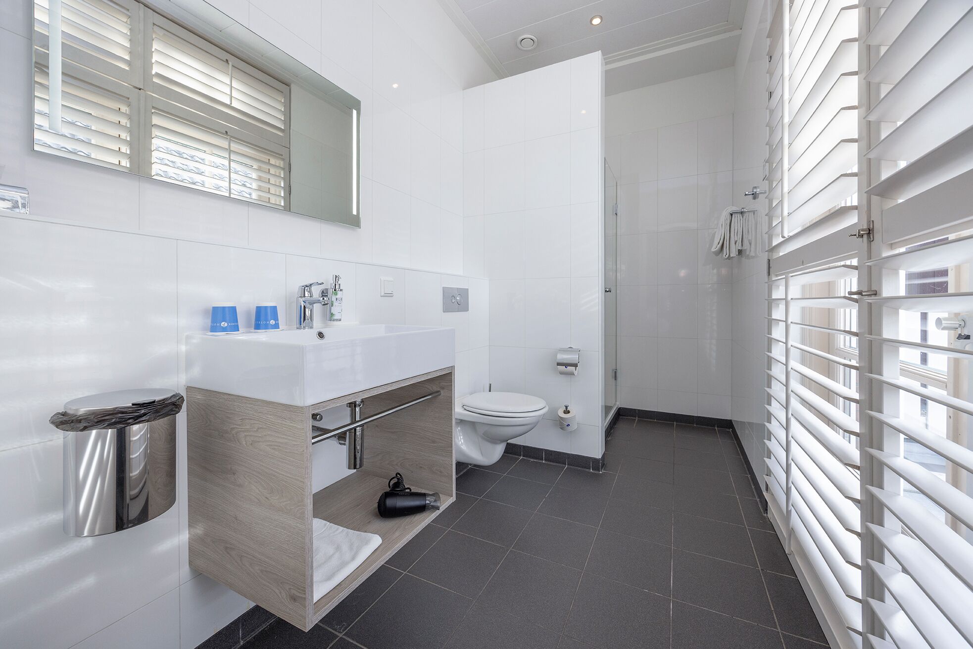 A modern bathroom with a white sink, mirror, and toilet.