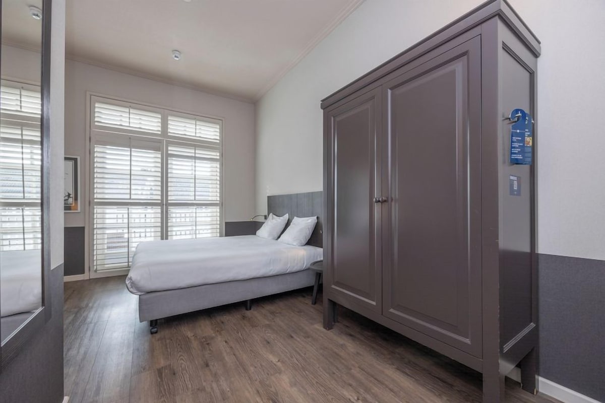 Un dormitorio con cama, armario y ventana con persianas.