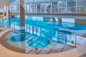 Una piscina interior con varias pistas de natación, zona de hidromasaje y una plataforma de observación.