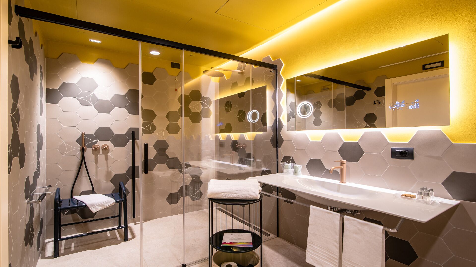 Un bagno moderno con box doccia in vetro, un lavandino bianco con un rubinetto e un portascopevoli.