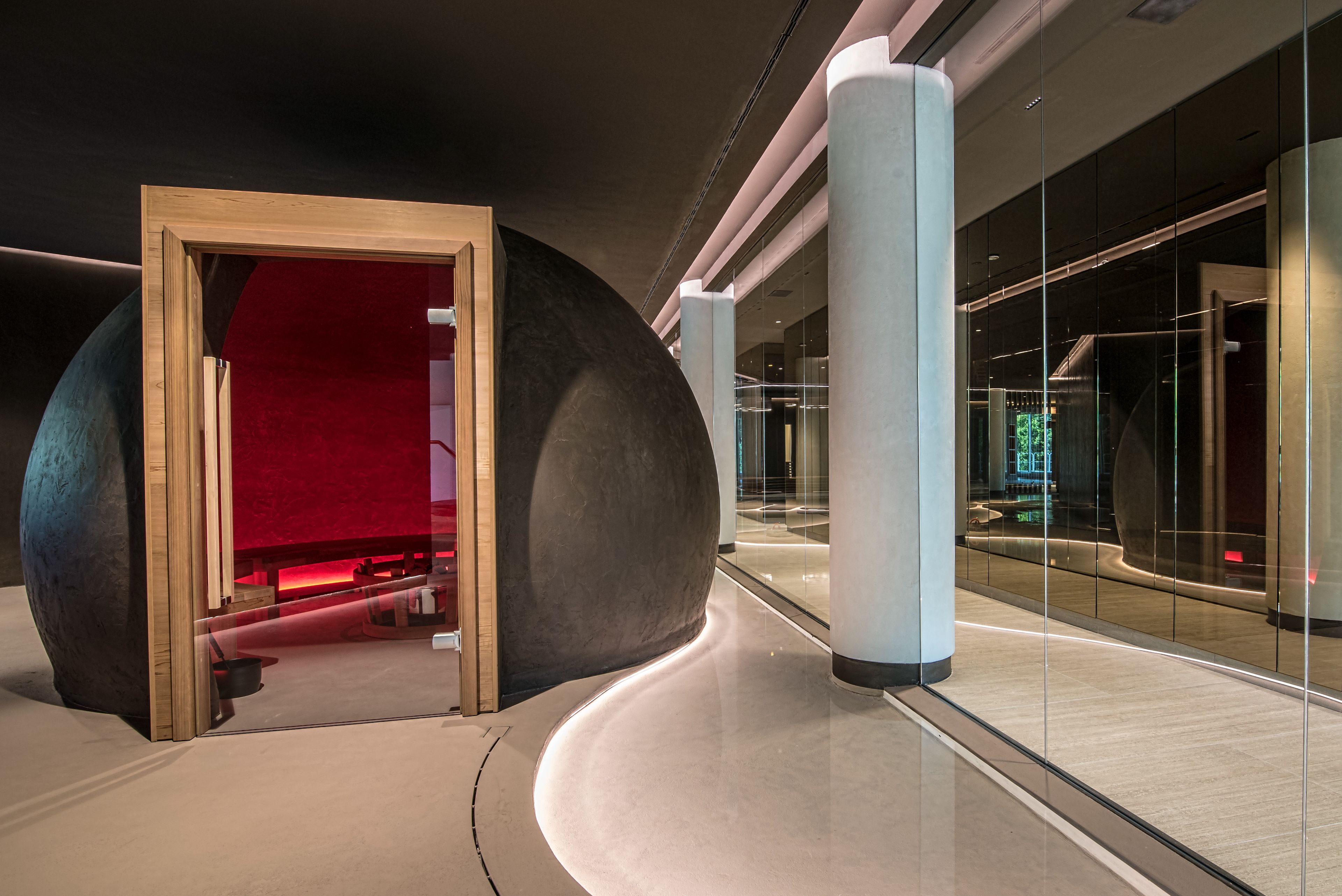 A modern interior with a curved pathway, a large spherical structure, and a wooden-framed doorway.