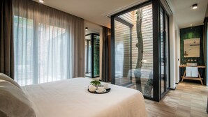 Una habitación de hotel moderna con una cama grande, un área de comedor con una bandeja de té y vista al exterior de madera.