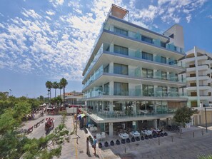 A modern multi-story hotel with outdoor seating areas and a glass facade. - Kyrat Amarac (Son Servera)