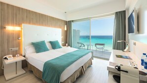 Une chambre d’hôtel avec un lit, une table de chevet, un bureau, une chaise et une vue sur la mer.
