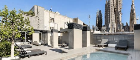 Una piscina al aire libre, sombrillas, sillones reclinables de piscina