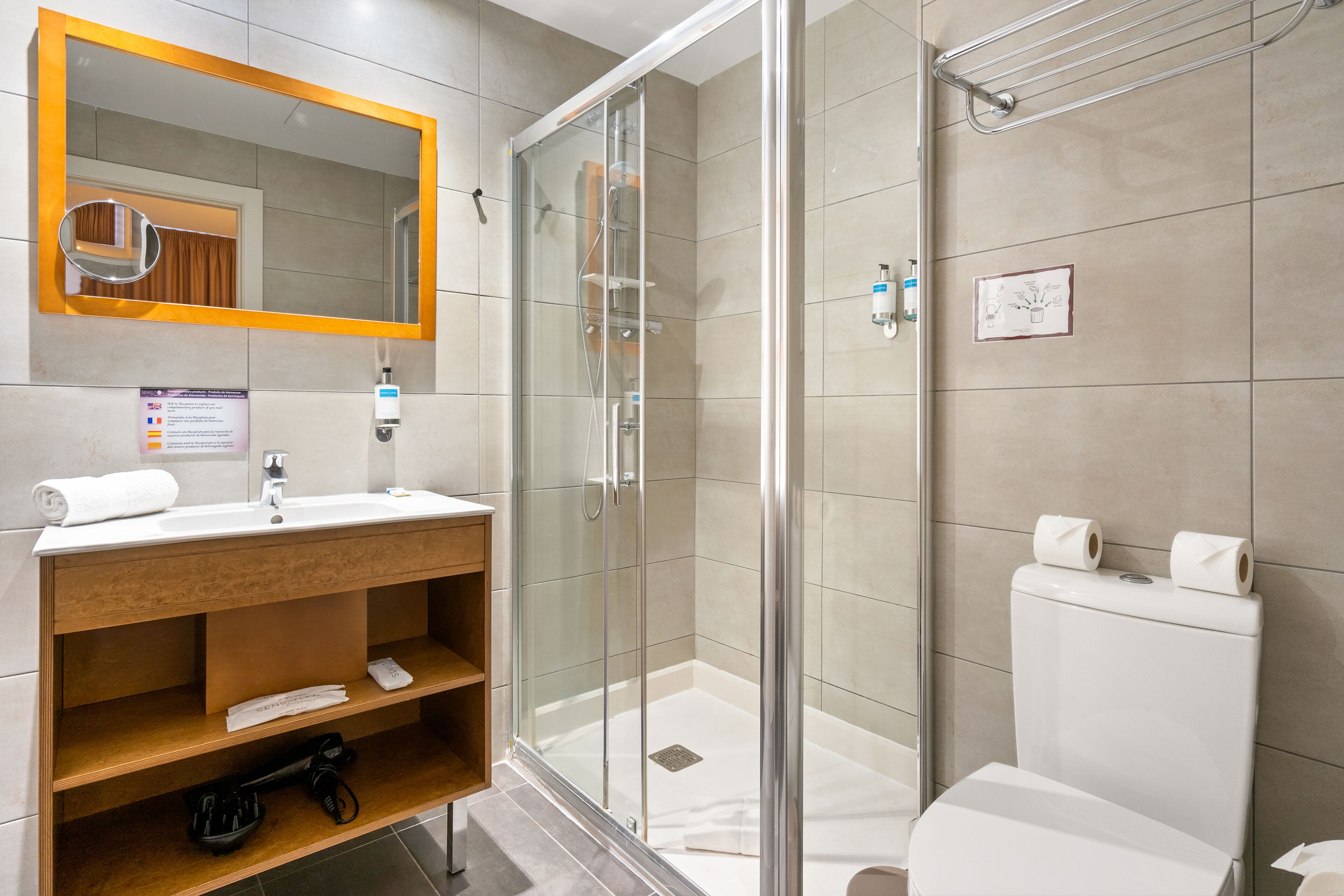 A modern bathroom with a glass-enclosed shower, a white sink, and a wooden vanity.