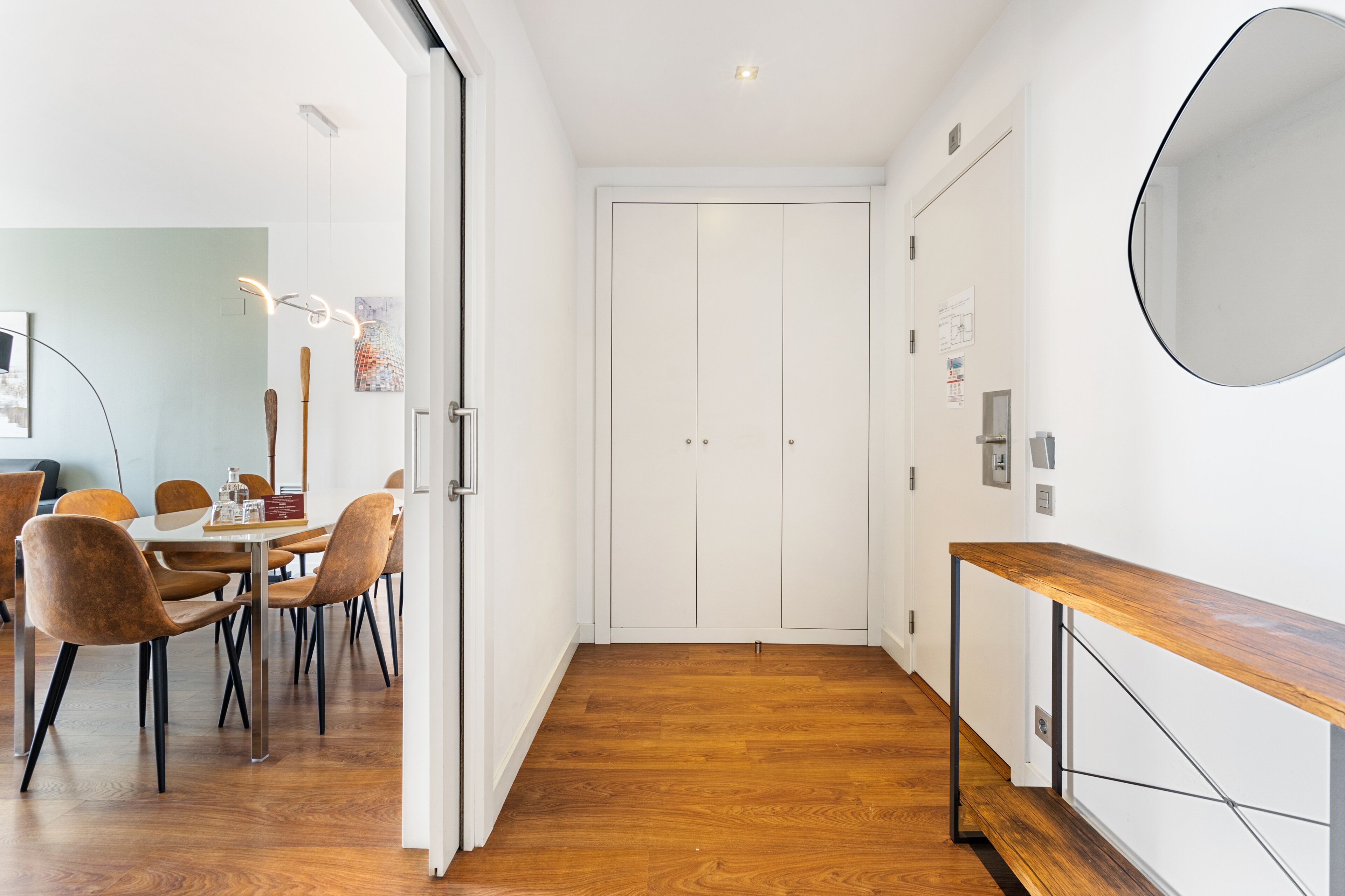 A modern interior with a dining area, wooden flooring, and a white door.