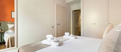 A hotel room with a large bed, two doors, a mirror, and a bathroom visible through an open door.