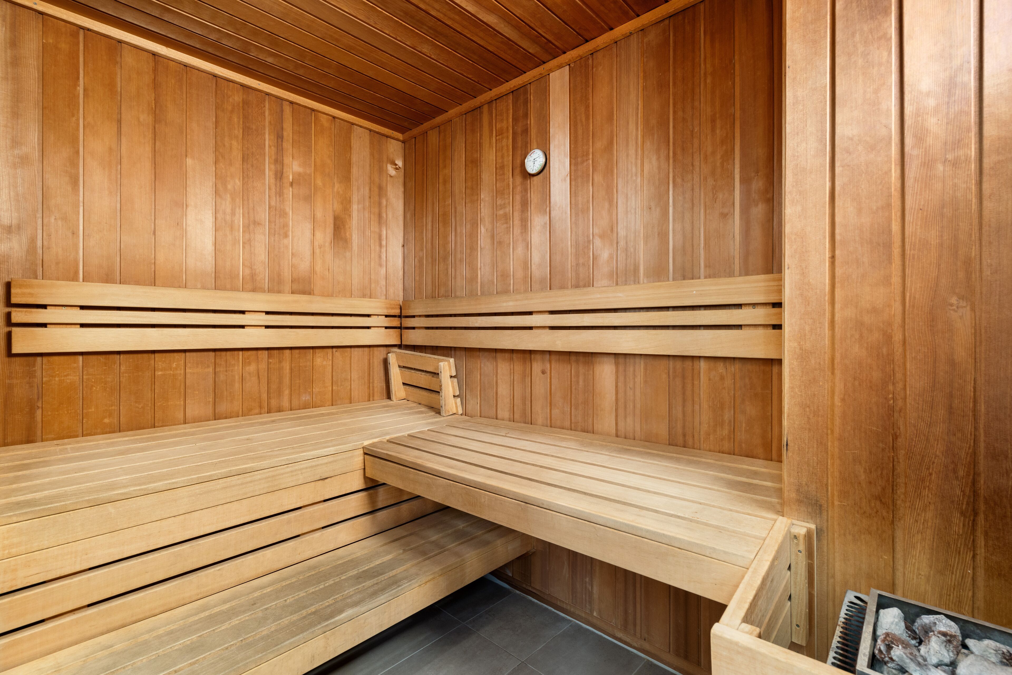 A wooden sauna with benches and a clock on the wall.