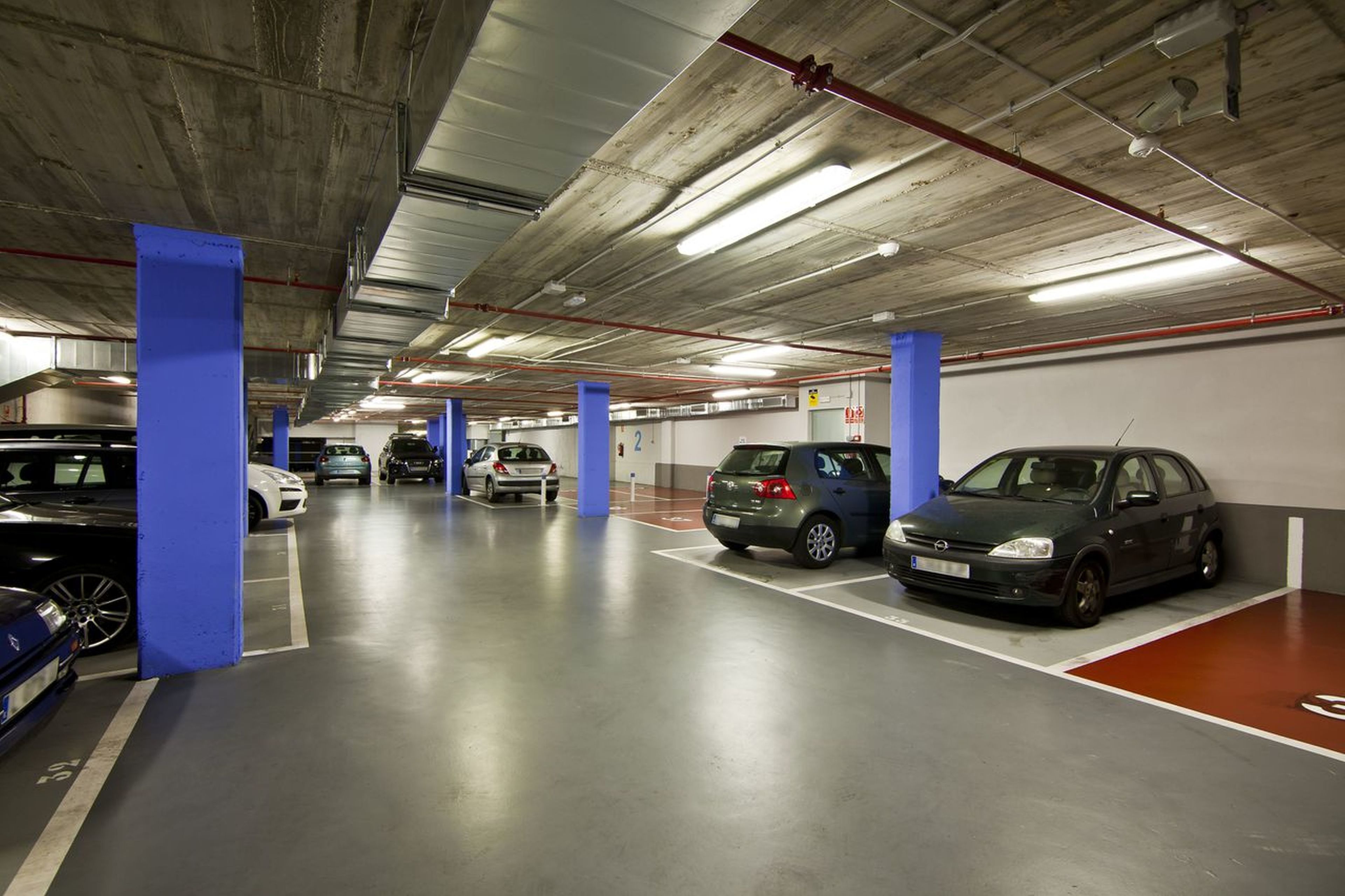 Un aparcamiento subterráneo de varios niveles con varios coches estacionados en plazas designadas.