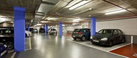 Un aparcamiento subterráneo de varios niveles con varios coches estacionados en plazas designadas.