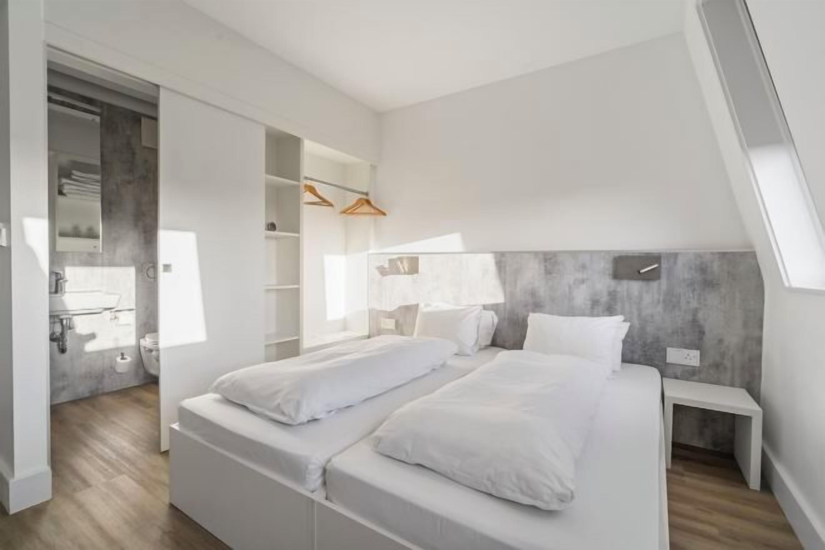 Une chambre à coucher moderne avec un lit de style industriel, des étagères intégrées et un dressing.