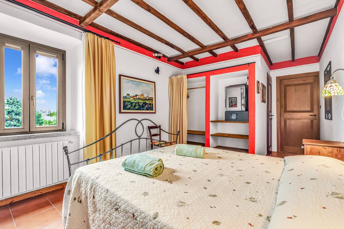 Un dormitorio con una cama, una ventana, una puerta y un marco rojo en la pared.
