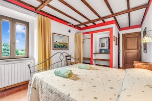 Un dormitorio con una cama, una ventana, una puerta y un marco rojo en la pared.