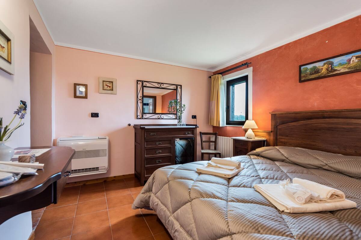 Un dormitorio con cama, cómoda, espejo y ventana con cortinas.