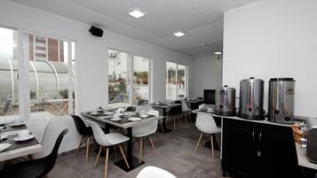 A modern kitchen with white and black furnishings, large windows, and stainless steel appliances.
