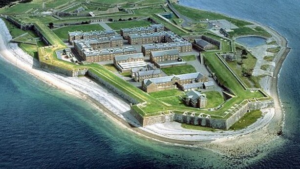 An aerial view of a coastal fort with multiple buildings, a surrounding moat, and a beach area. - Dolphin Bay Suites (Inverness)