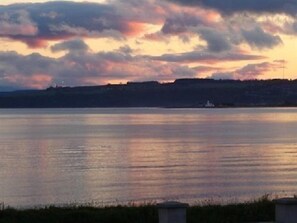 A calm body of water with a distant shoreline and a small boat. - Dolphin Bay Suites (Inverness)