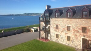 A stone building with a balcony overlooking a body of water. - Dolphin Bay Suites (Inverness)