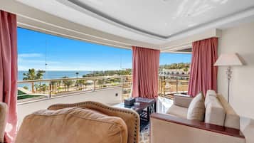 A hotel room with a balcony overlooking a beach and resort area.
