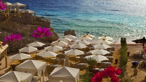 A coastal hotel with multiple beach umbrellas and tents, overlooking the sea.