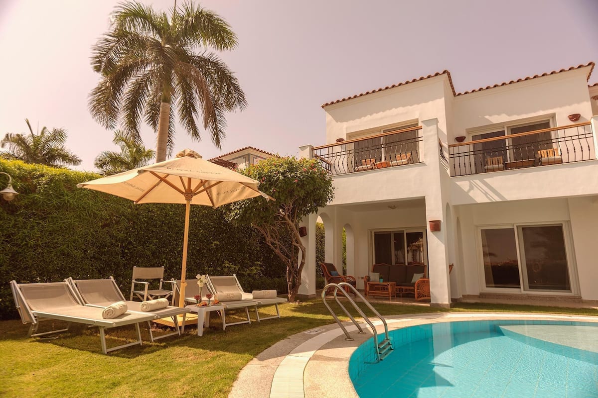 A poolside area with lounge chairs, a table, and an umbrella.