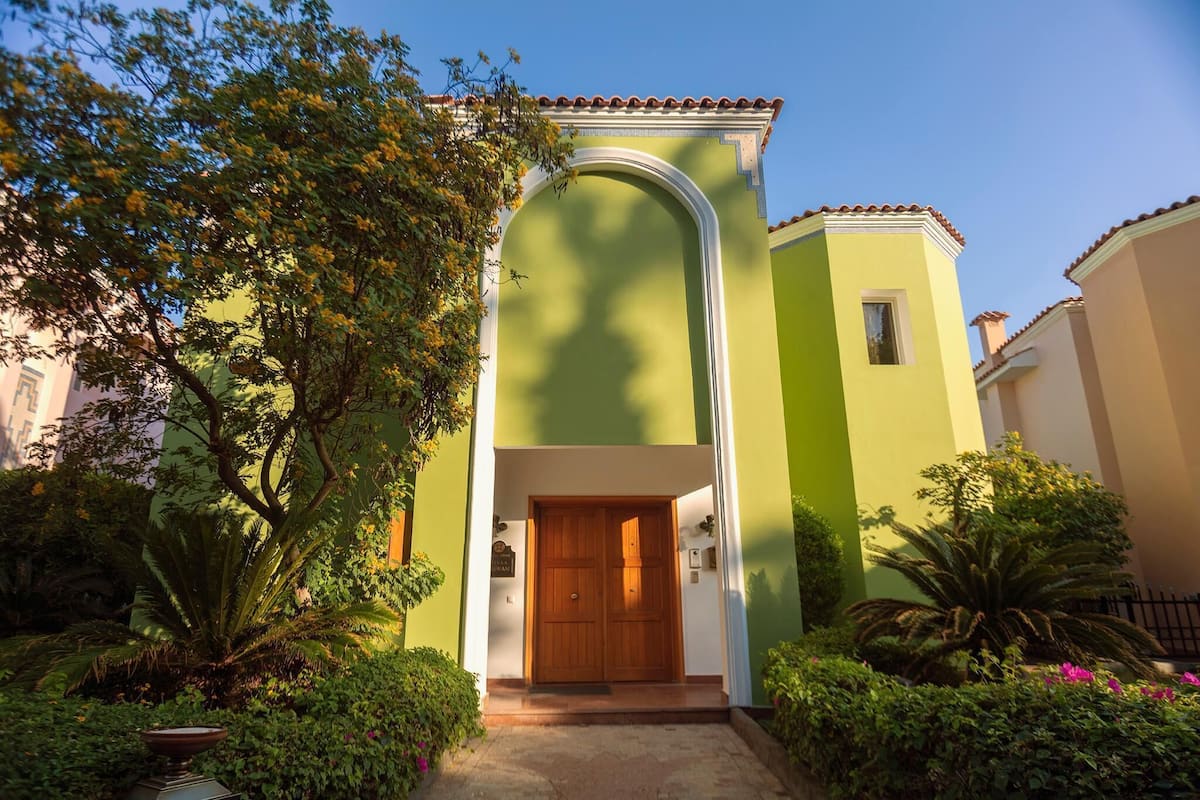 A building with a green facade, a wooden door, and a tiled roof.