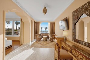 Habitació d'hotel amb balcó, sofà, taula de dinar i televisió.