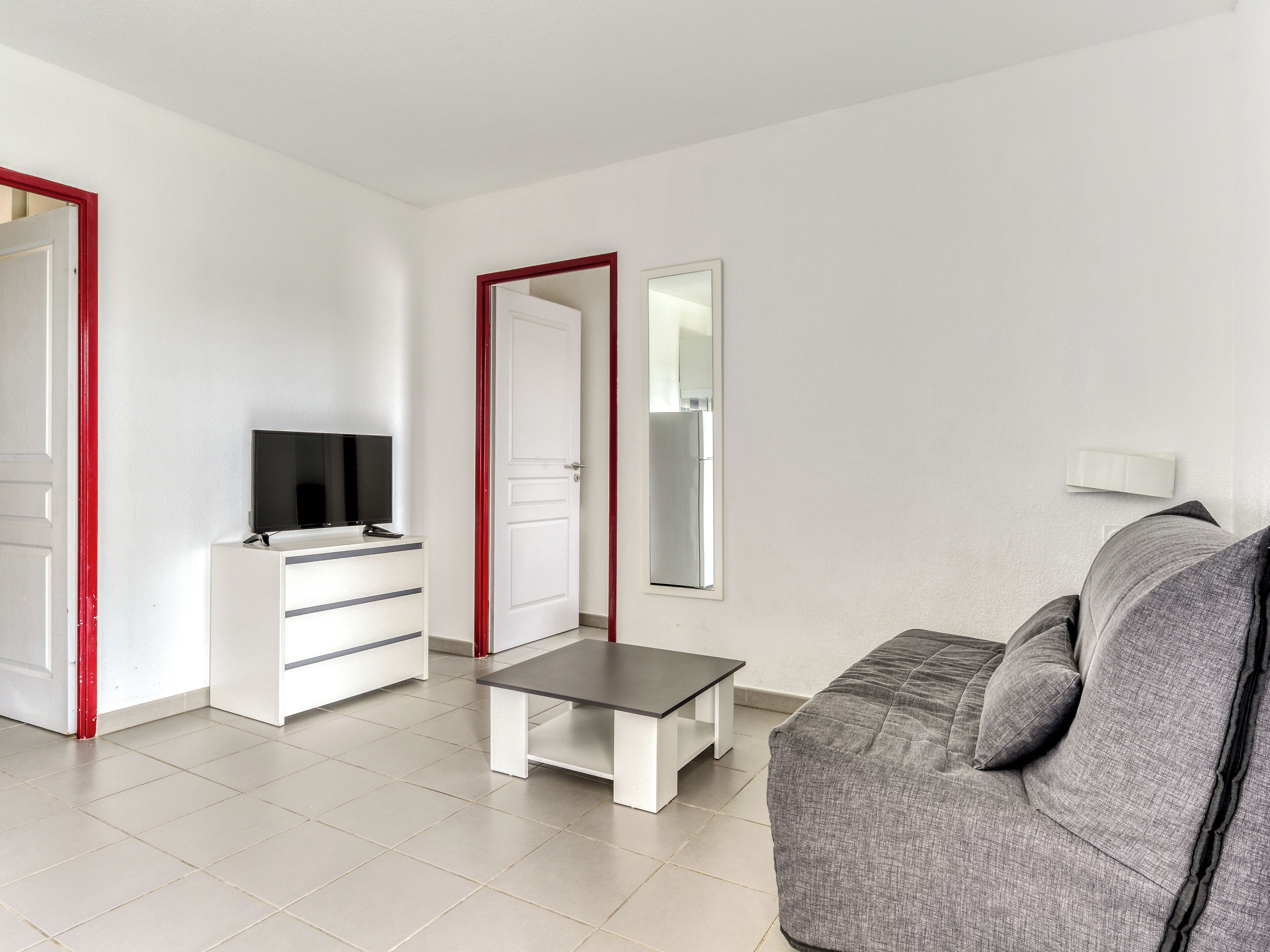A modern living room with a grey sofa, a white TV stand, and a small table.