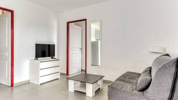 Una sala de estar moderna con un sofá gris, un mueble blanco para televisor y una mesita.