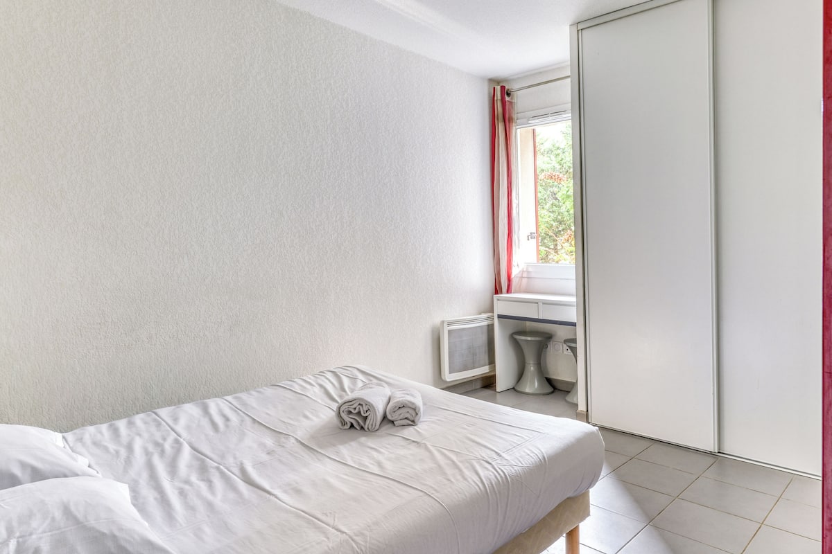 Une chambre à coucher avec un lit, une table de chevet, un miroir et une armoire.