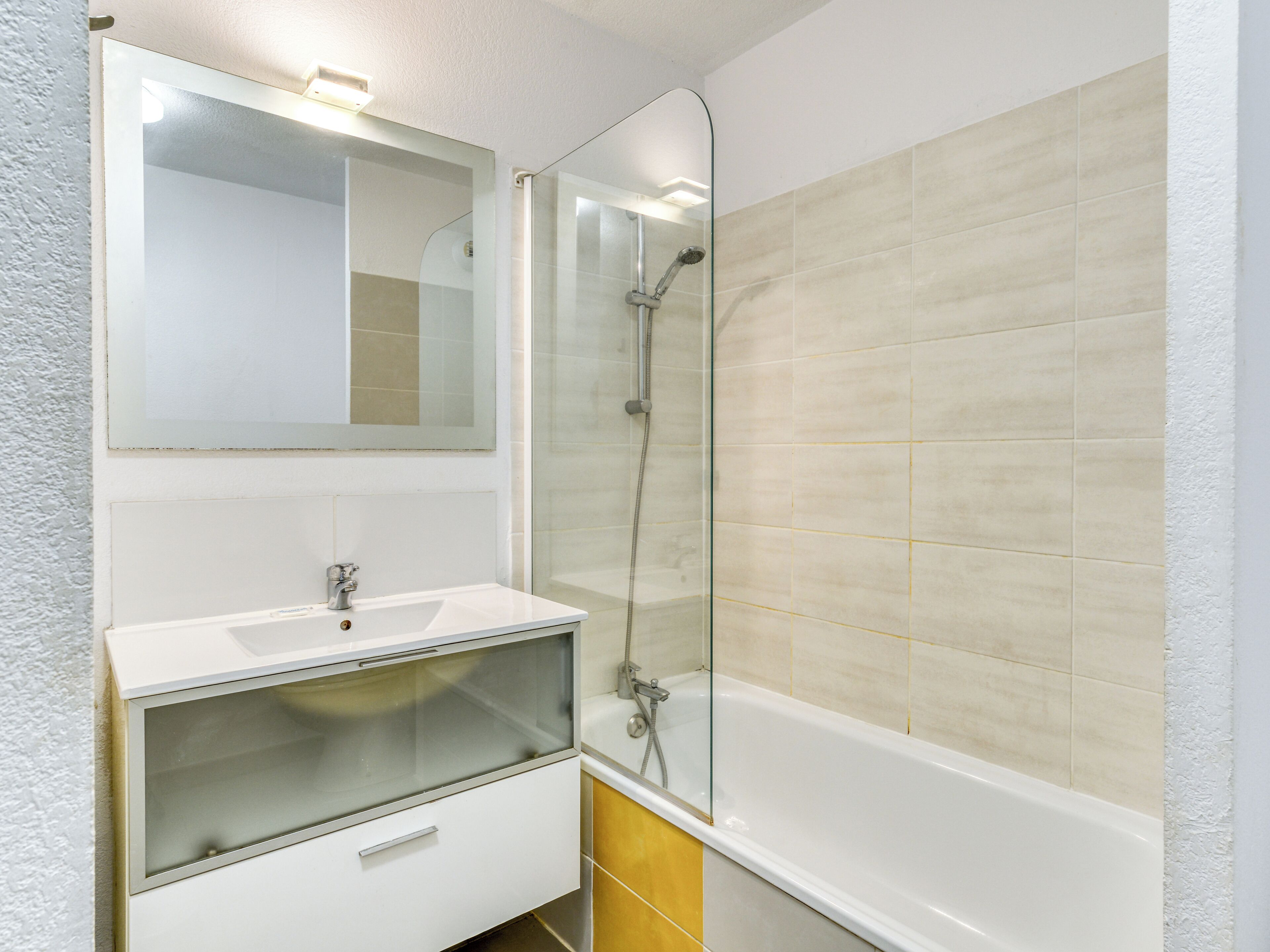 A bathroom with a glass-enclosed shower, a white sink, and a mirror above the sink.