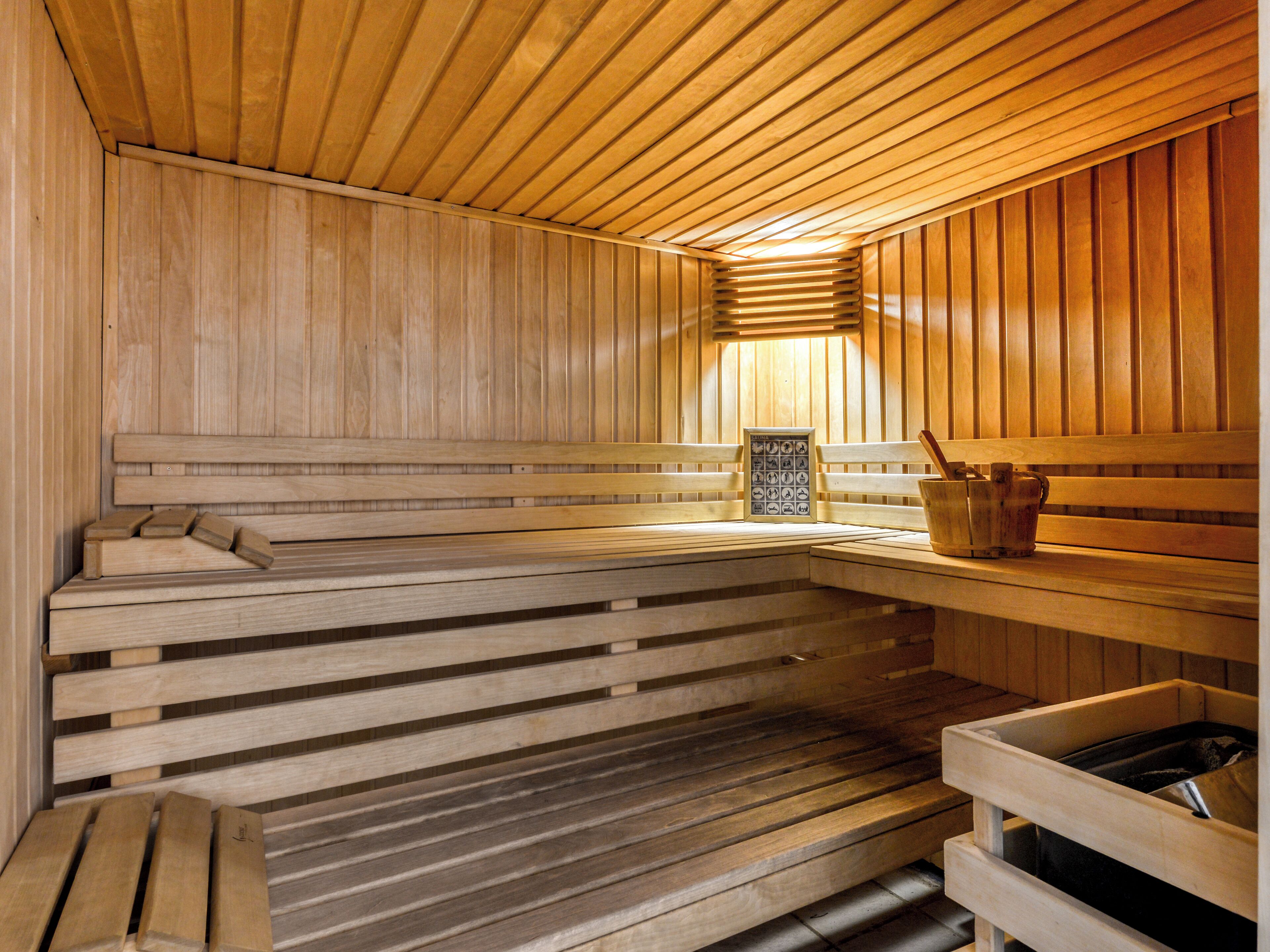 A wooden sauna with benches and a bench with a bucket.