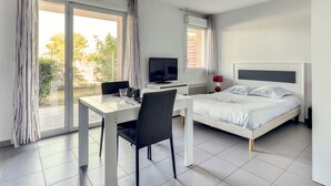Une chambre d’hôtel comprenant un lit, un bureau avec une chaise, une télévision et une fenêtre avec des rideaux.