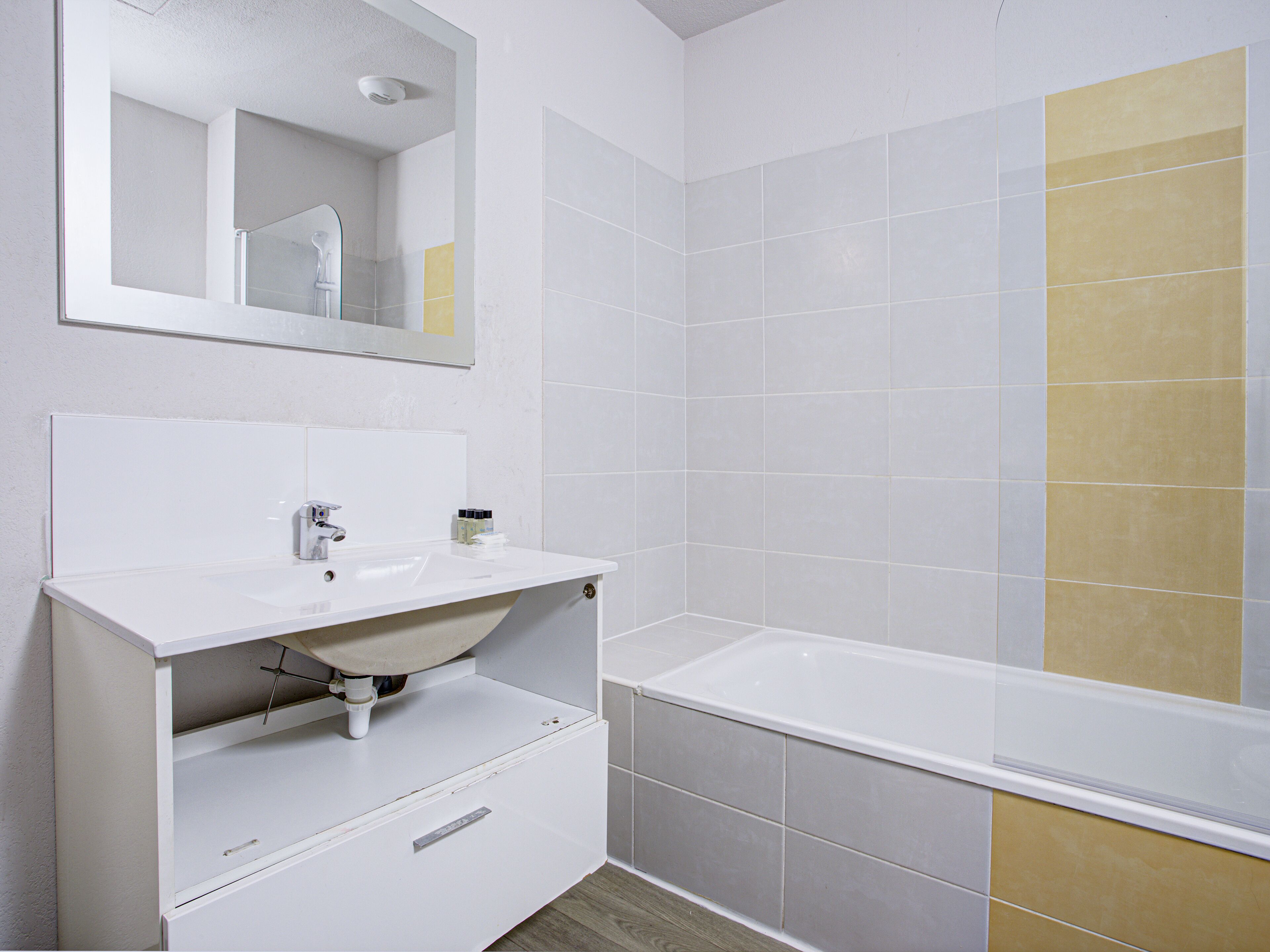 Un baño con lavamanos, espejo y bañera blancos.