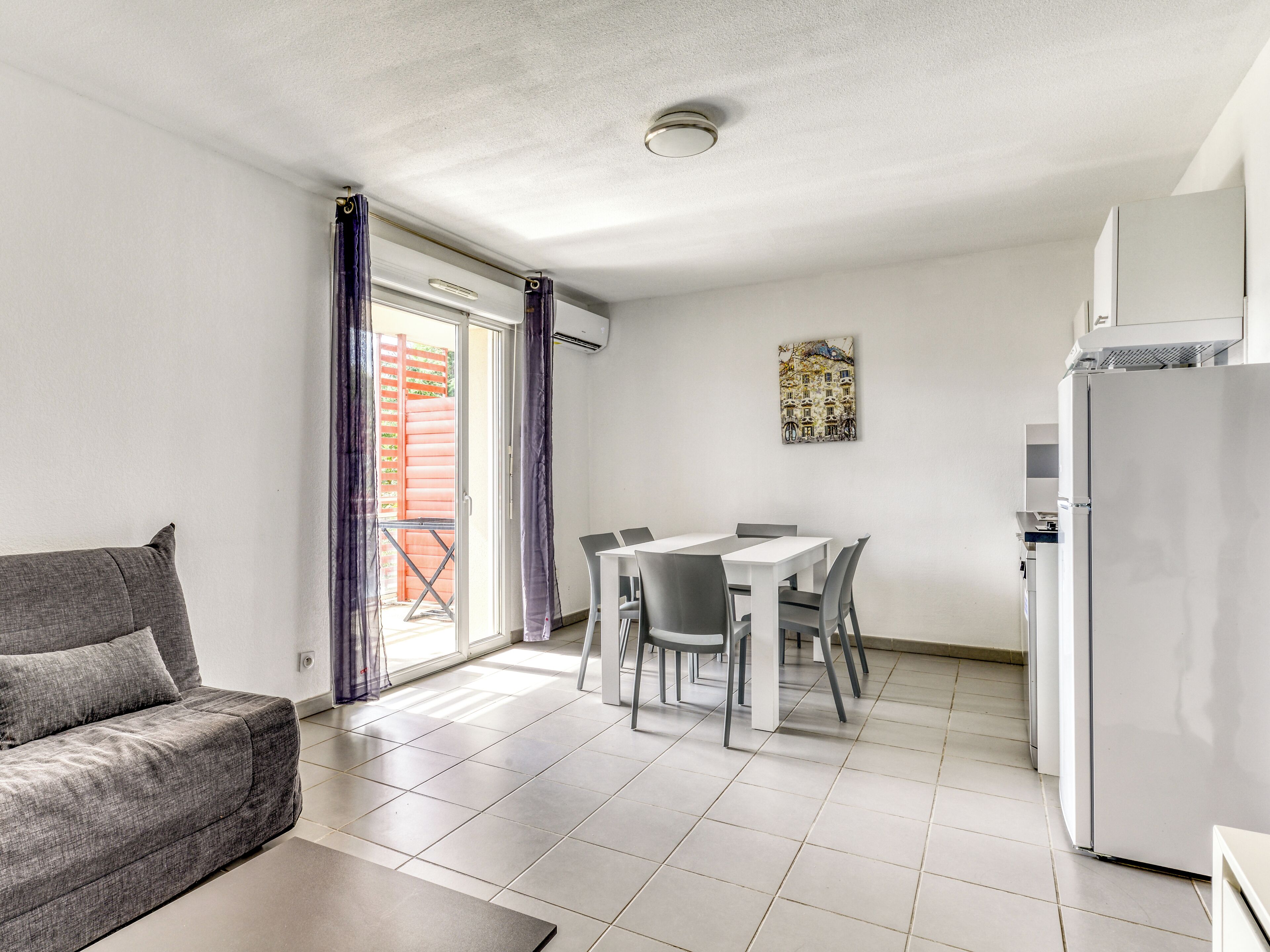 Une cuisine moderne avec un coin repas, un canapé et une porte-fenêtre coulissante donnant sur un espace extérieur.