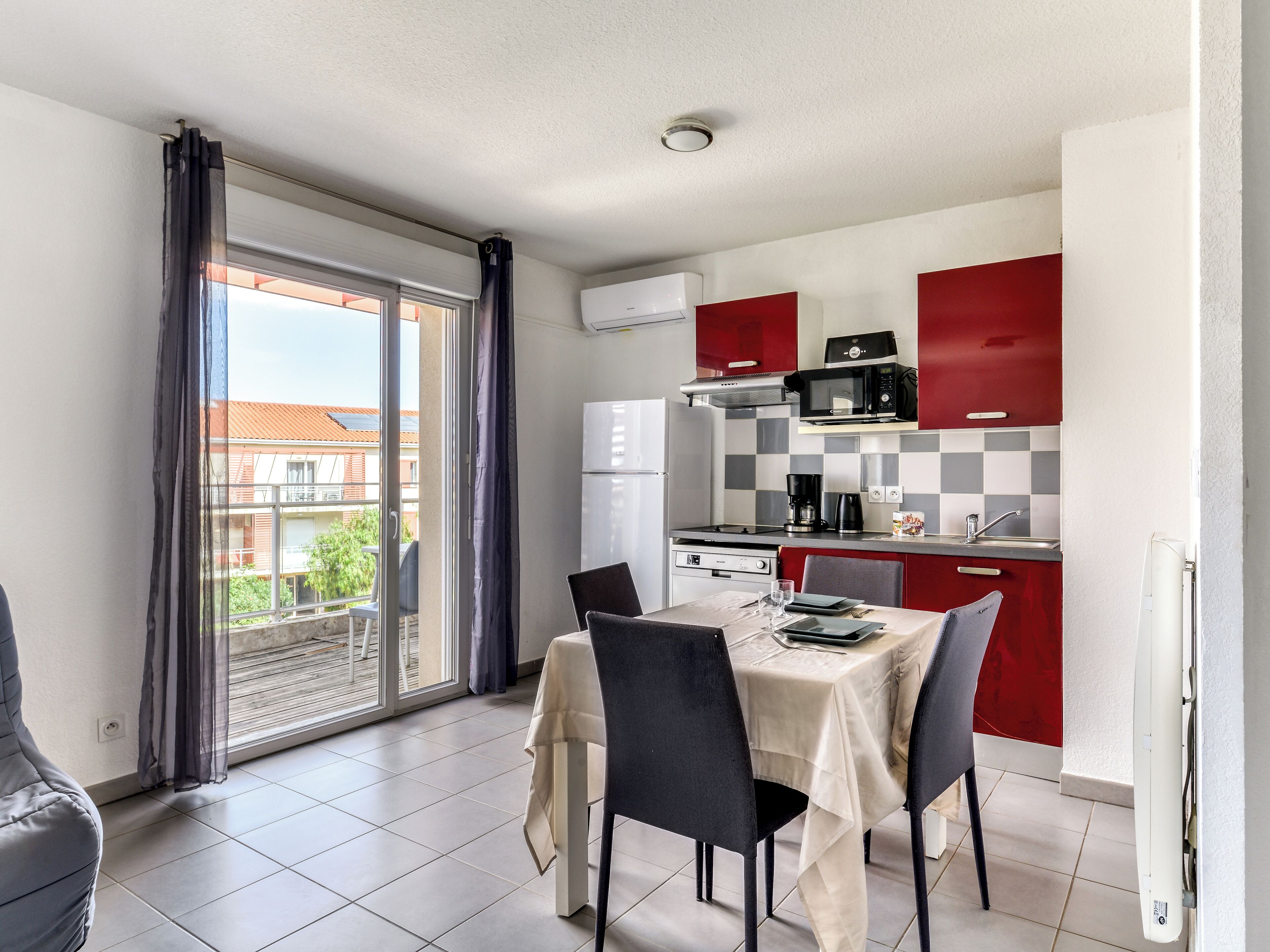 A compact kitchen with a dining area, a view through a sliding glass door, and a red and white color scheme.
