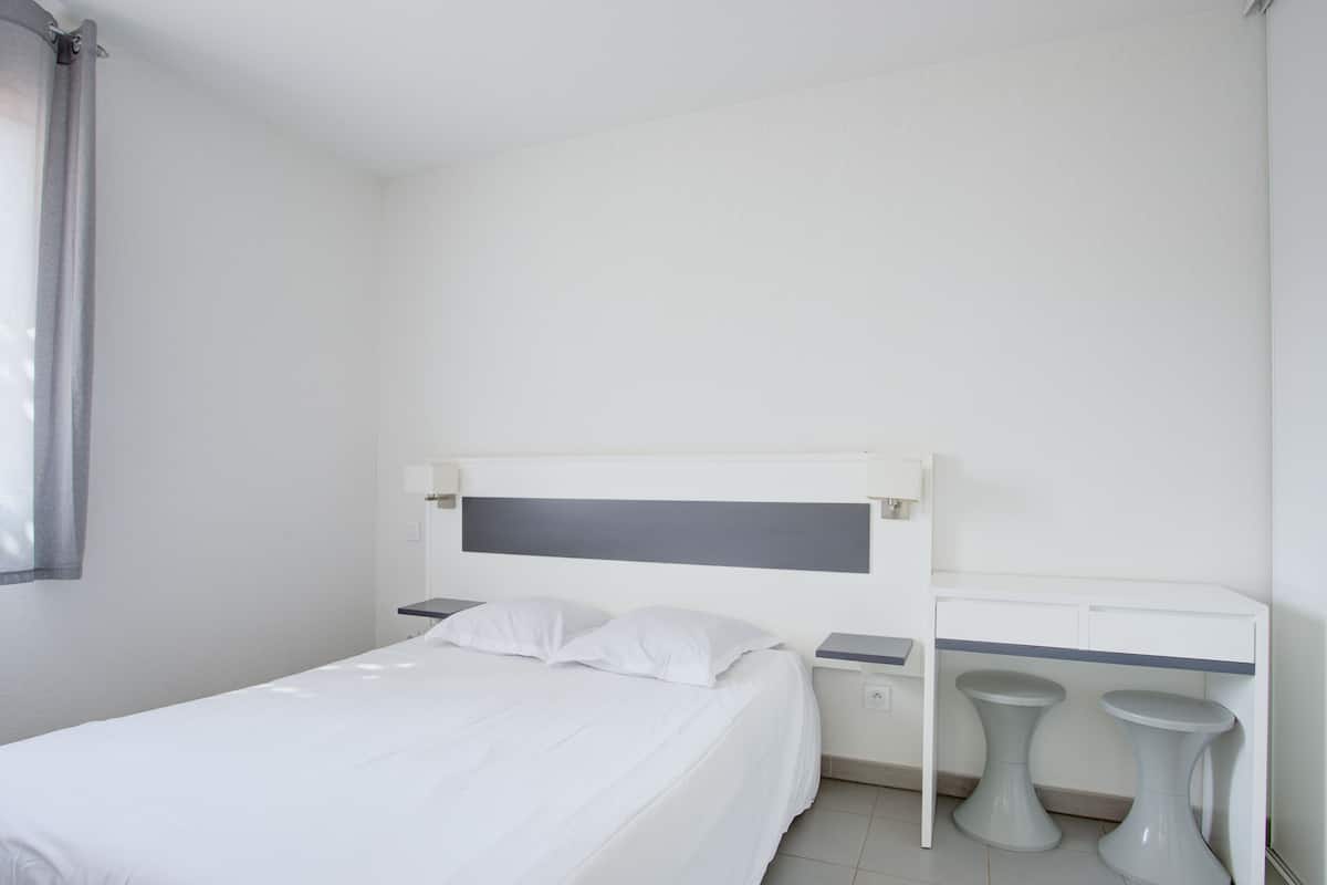 Une chambre à coucher au style minimaliste, avec un lit, des tables de chevet et une petite table de nuit.