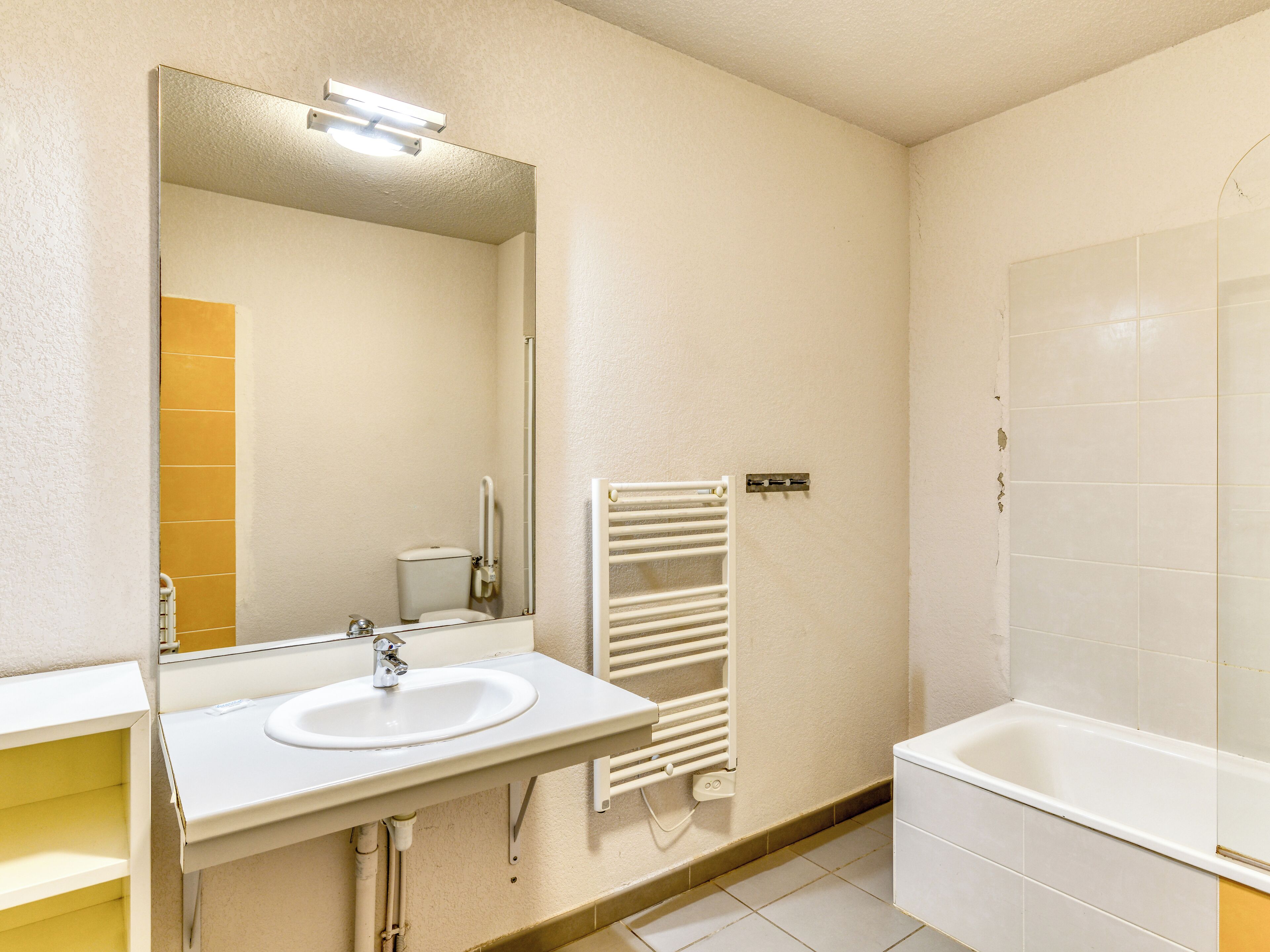 Un baño con lavamanos, espejo, inodoro y bañera.