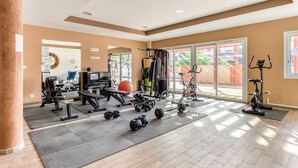 Une salle de sport spacieuse, dotée de divers appareils d’exercice, de grandes fenêtres et offrant une vue sur l’extérieur.