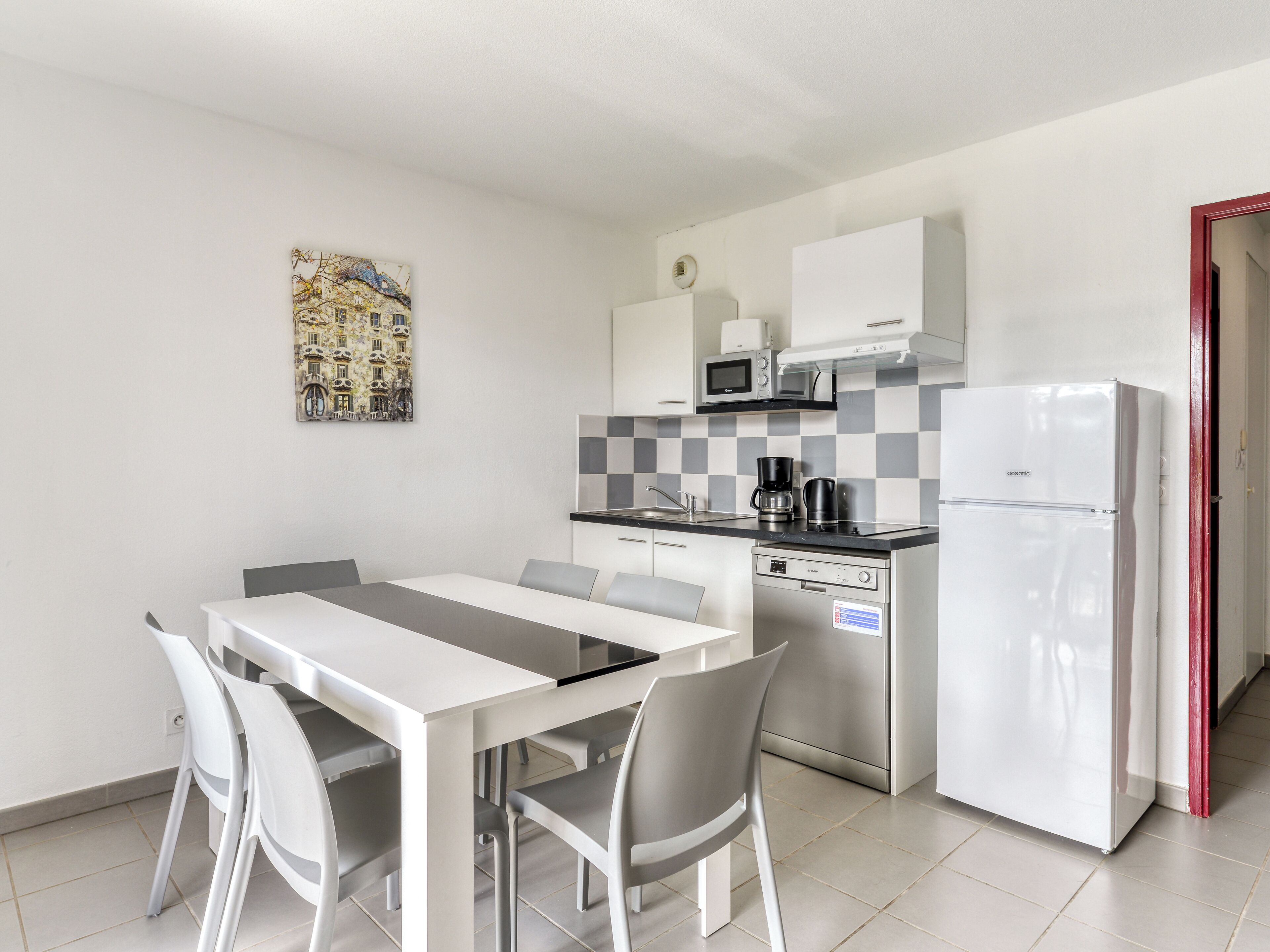 Cocina compacta con mesa, sillas, refrigerador, microondas y cafetera.