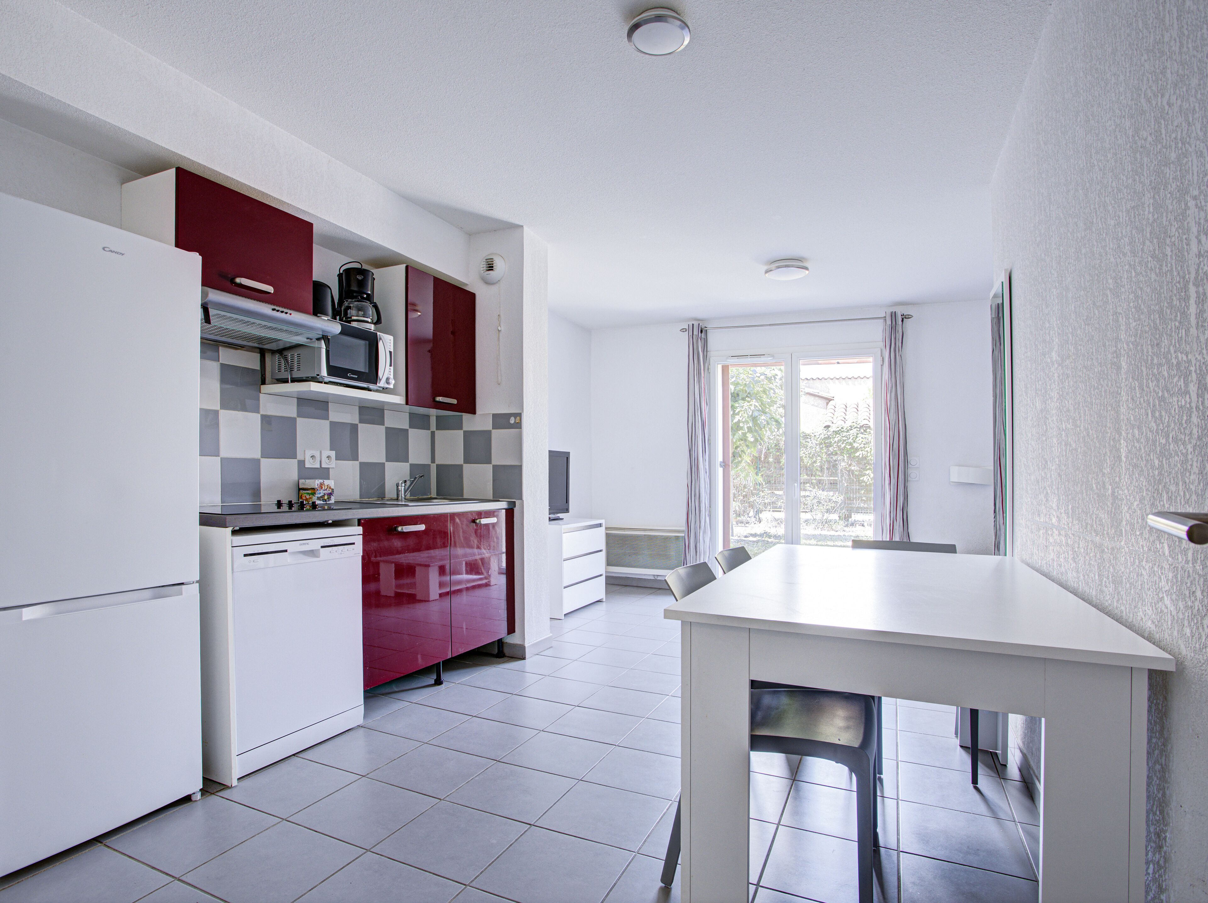 A compact kitchen with white and red cabinets, a microwave, and a dishwasher.
