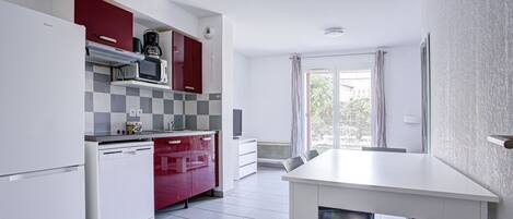A compact kitchen with white and red cabinets, a microwave, and a dishwasher.
