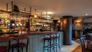 A bar area with multiple stools, a bar counter, and a variety of glassware and bottles. - The Northey Arms (Corsham)