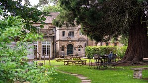 A courtyard with stone benches, a picnic table, and a large tree. - The Northey Arms (Corsham)