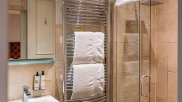 A modern bathroom with a glass shower enclosure, a white sink, and a towel rack.