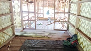 A wooden structure with a thatched roof, wooden walls, and a black mat on the floor. - Masipai Guest House (Tingwon Island)