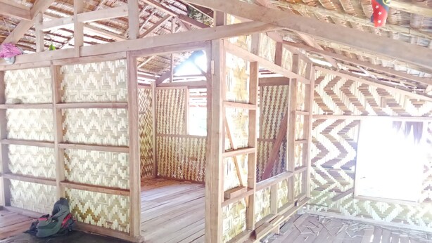 A wooden structure with a thatched roof, featuring a patterned wall and a bench area. - Masipai Guest House (Tingwon Island)